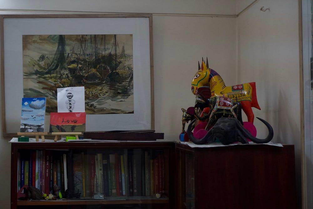 A shelf in Rafikun Nabi's home with a child's painting, an old sketch and painted toy horses