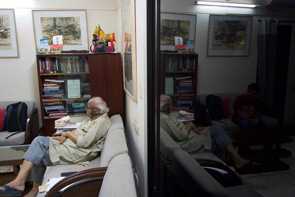 Rafikun Nabi seated in the drawing room, reflected in a mirrored wardrobe door