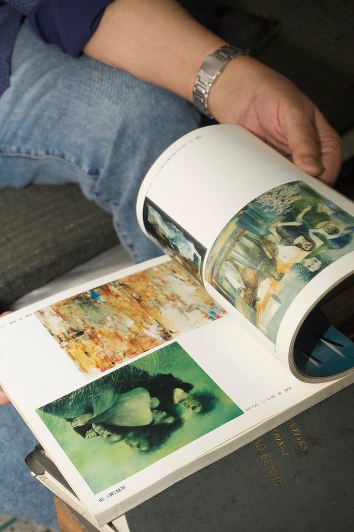 Hands holding open a catalogue of Mohammad Eunus's paintings