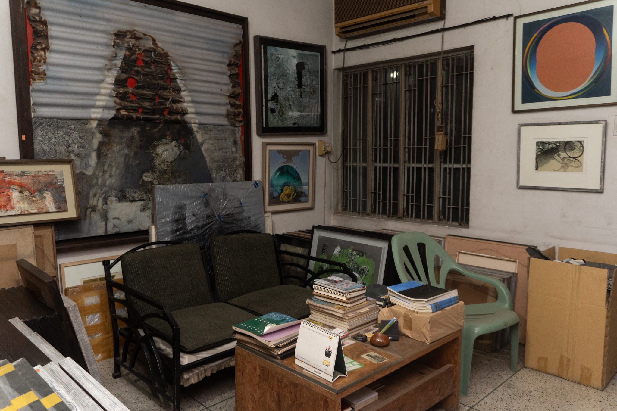 A sitting room inside the studio filled with framed paintings and sketchbooks
