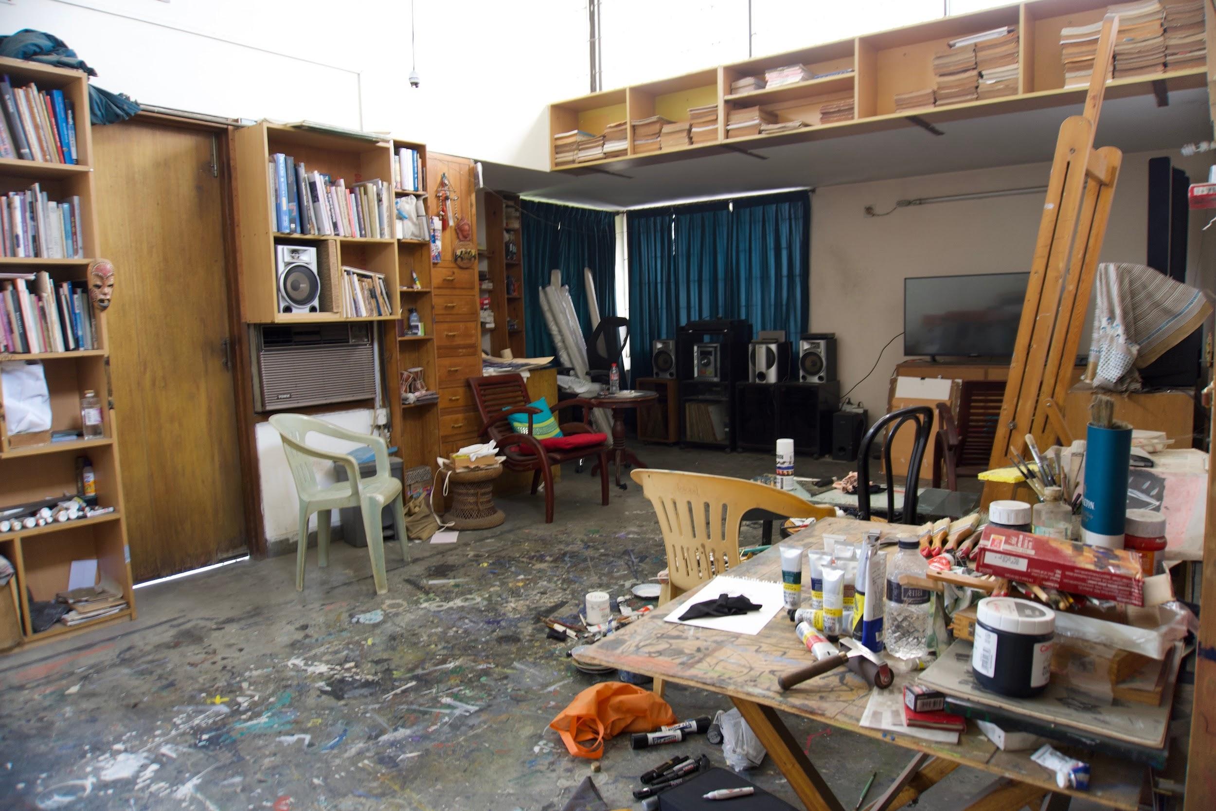 A wide view of Rafikun Nabi's third-floor studio, with bookshelves, easels and a paint-stained floor